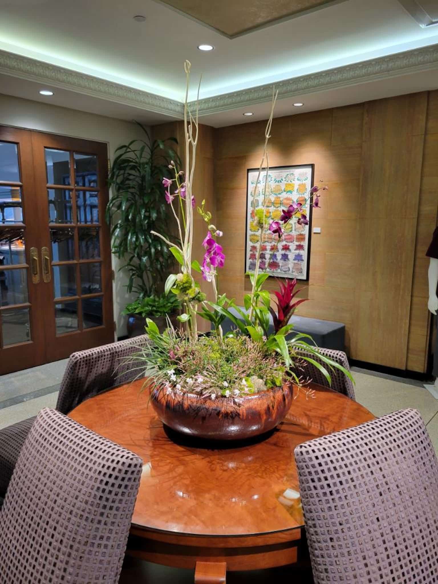 Colorful orchid and tropical plant arrangement in a glossy round ceramic bowl