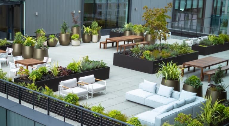 Wide rooftop view showing patterned planter layout with tables and lounging areas.