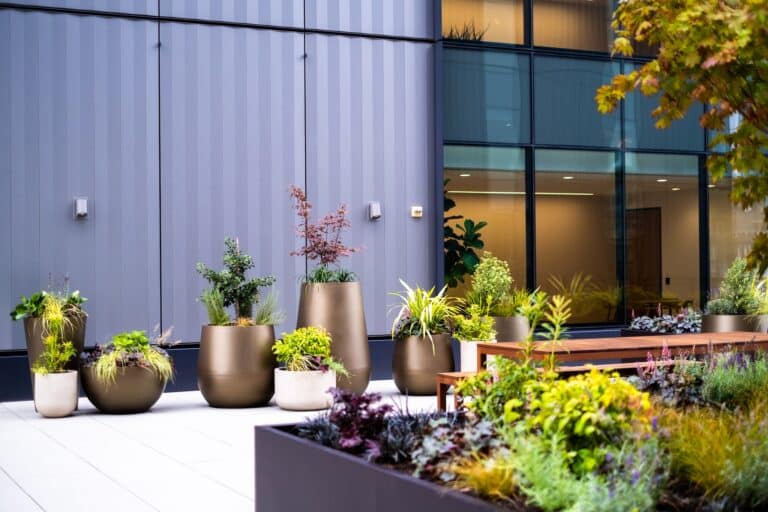 Assortment of bronze and cream outdoor planters in a rooftop courtyard with bench seating.