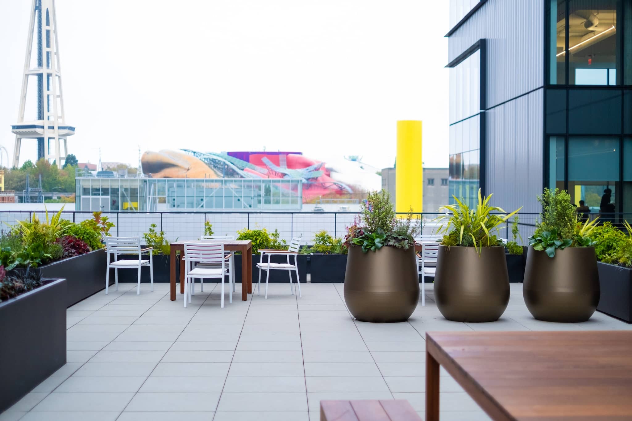 Rooftop planters with bronze finish positioned near tables, with the Space Needle in the background.